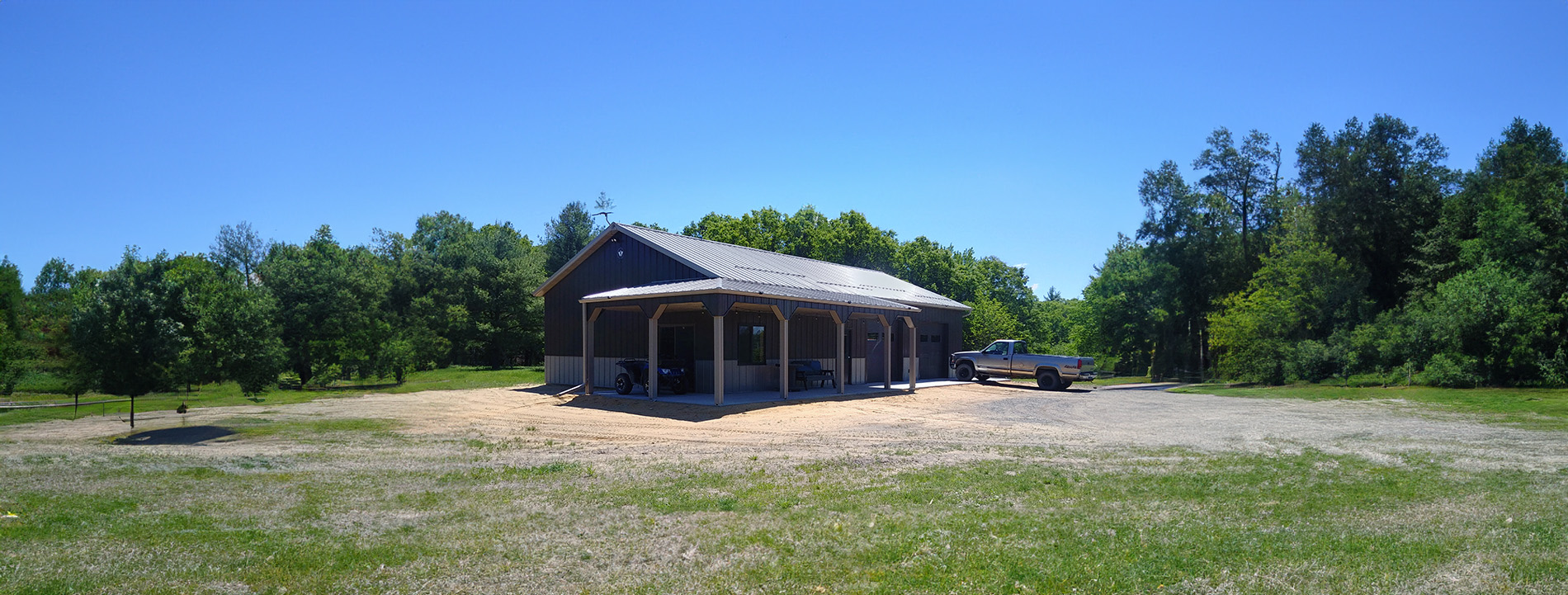 grey and beige suburban post frame workshop with wraparound porch and awning and a truck parked in front